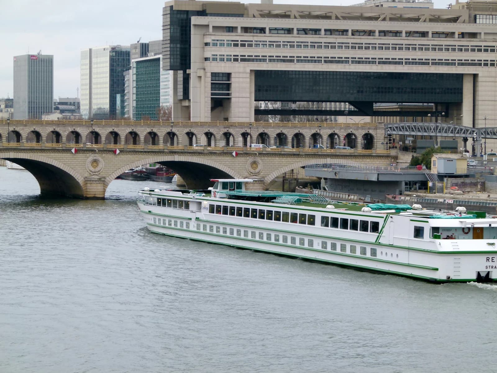 The Ministry of Finance building, Pont de Bercy bridge, and a boat on the Seine River in Paris.