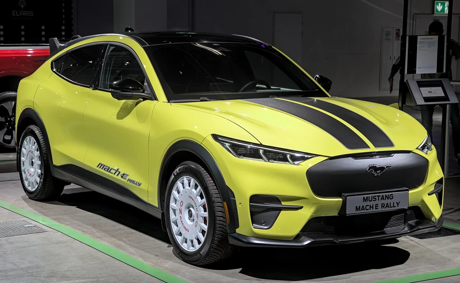 Bright yellow 2026 Ford Mustang Mach-E Rally electric SUV with black racing stripes.
