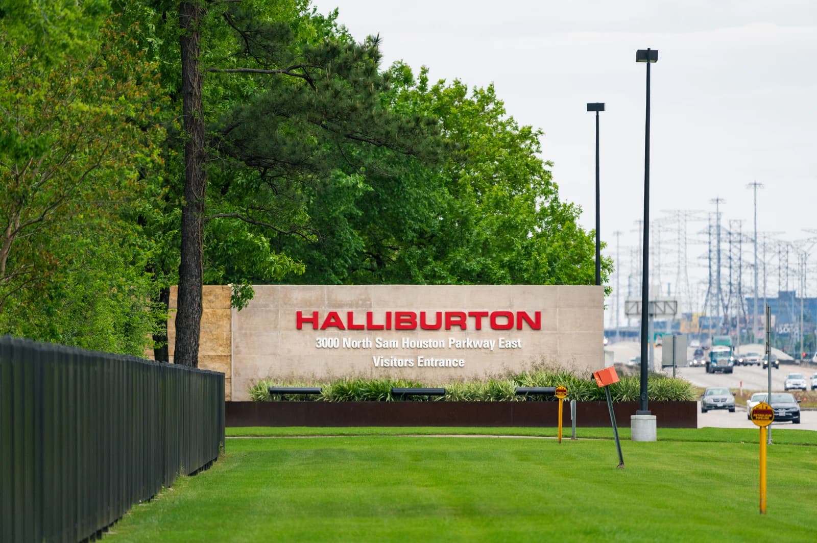 Halliburton corporate office headquarters sign in Houston, Texas, with a highway in the background.