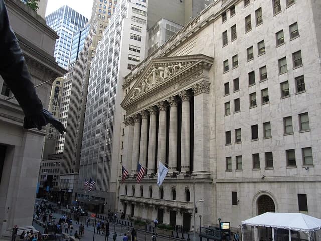 Exterior of the New York Stock Exchange building with columns and flags.