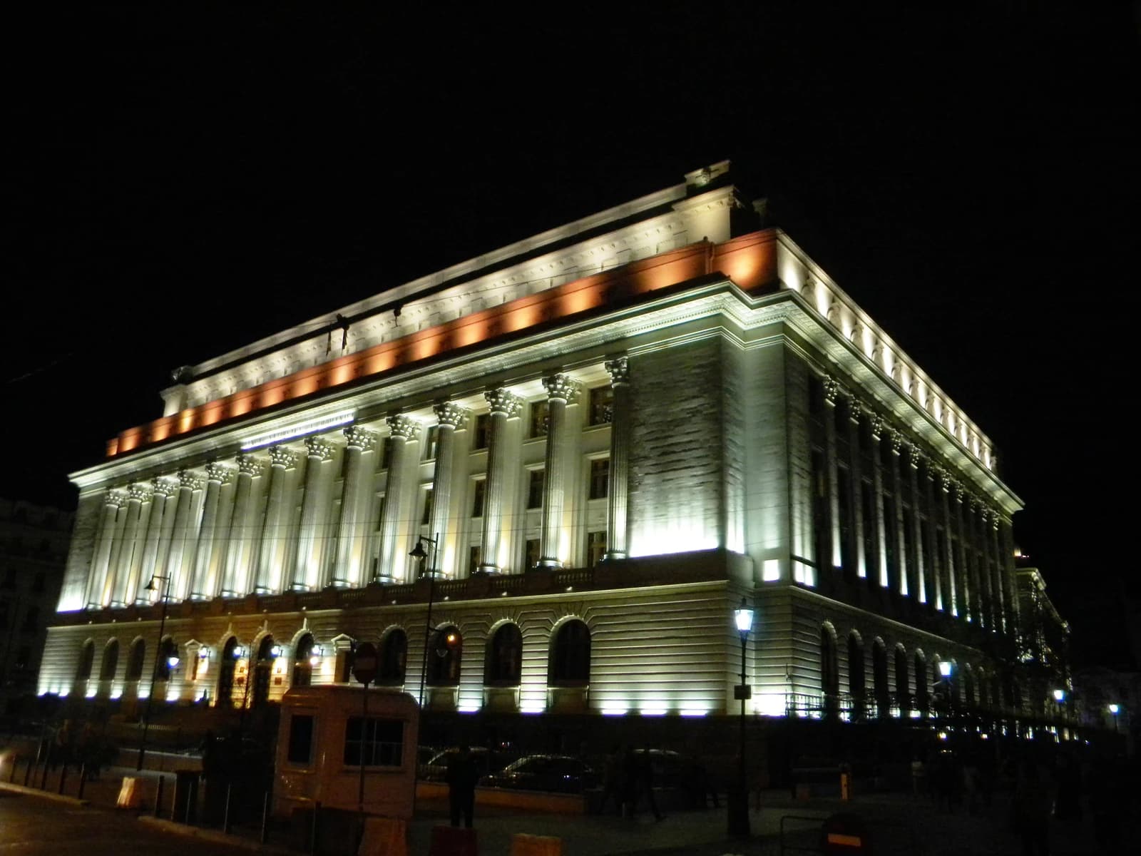 The illuminated classical facade of the National Bank of Romania building at night.