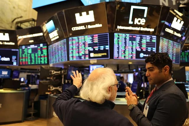 Andrew Aziz, financial professional, speaking with another man on a trading floor.