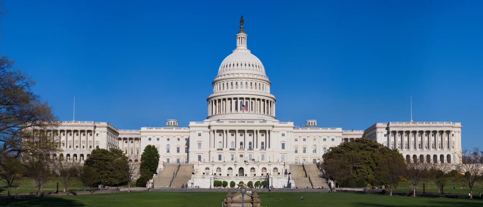 The United States Capitol Building, with its dome and columns, under a clear blue sky.