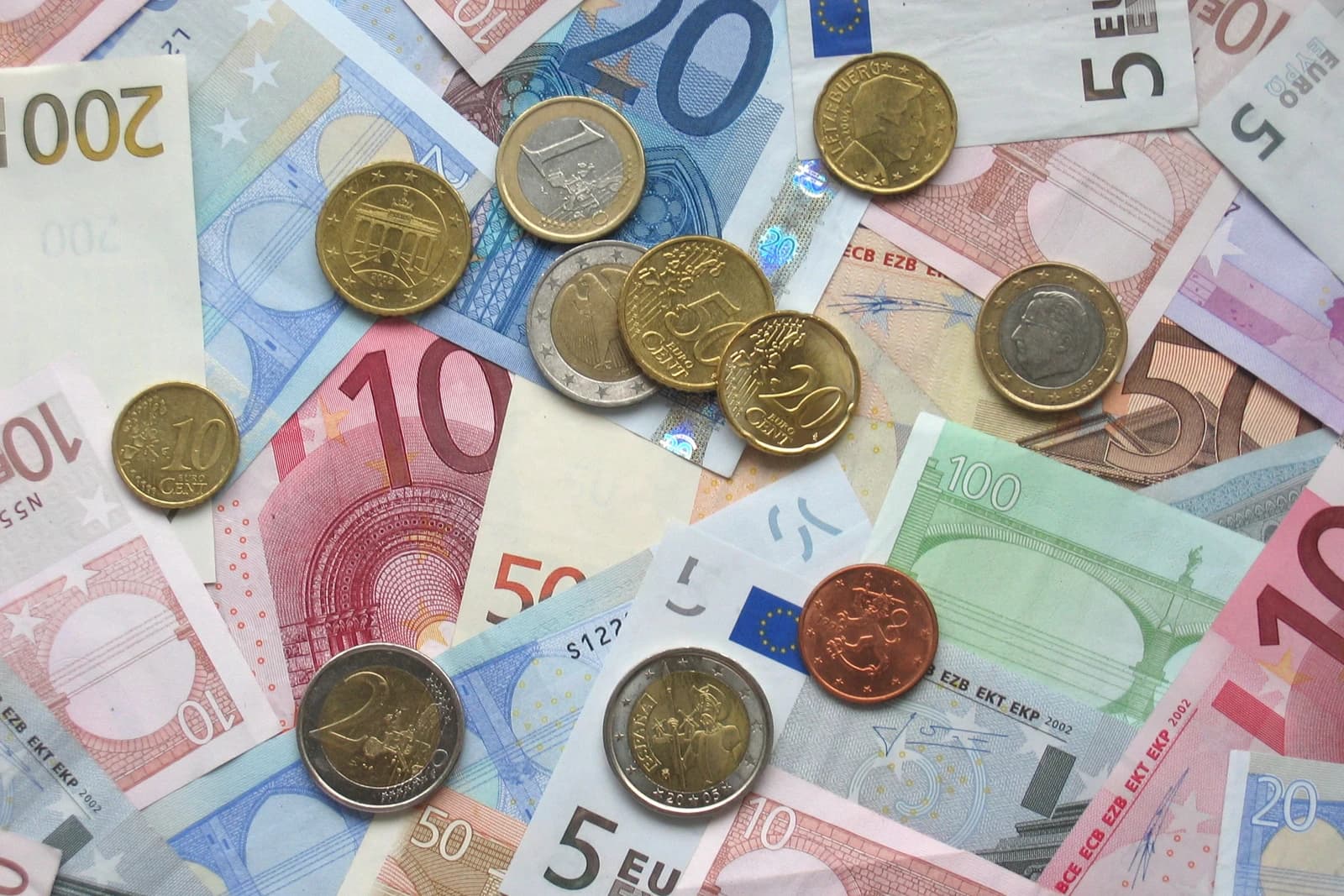 A close-up view of multiple Euro coins and banknotes of different values.
