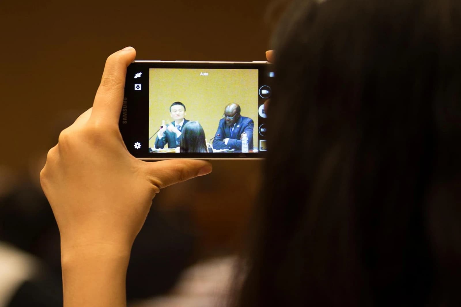 Audience member records Jack Ma, founder of Alibaba, speaking at a conference.