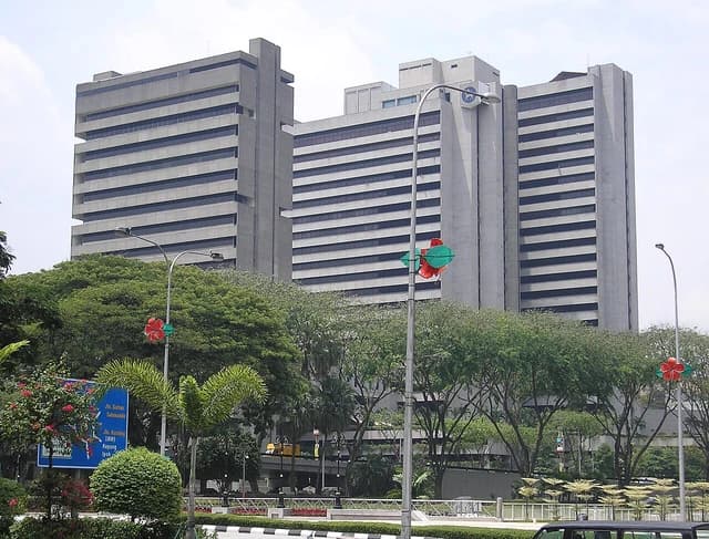 Central Bank of Malaysia headquarters, a tall concrete building, surrounded by trees.