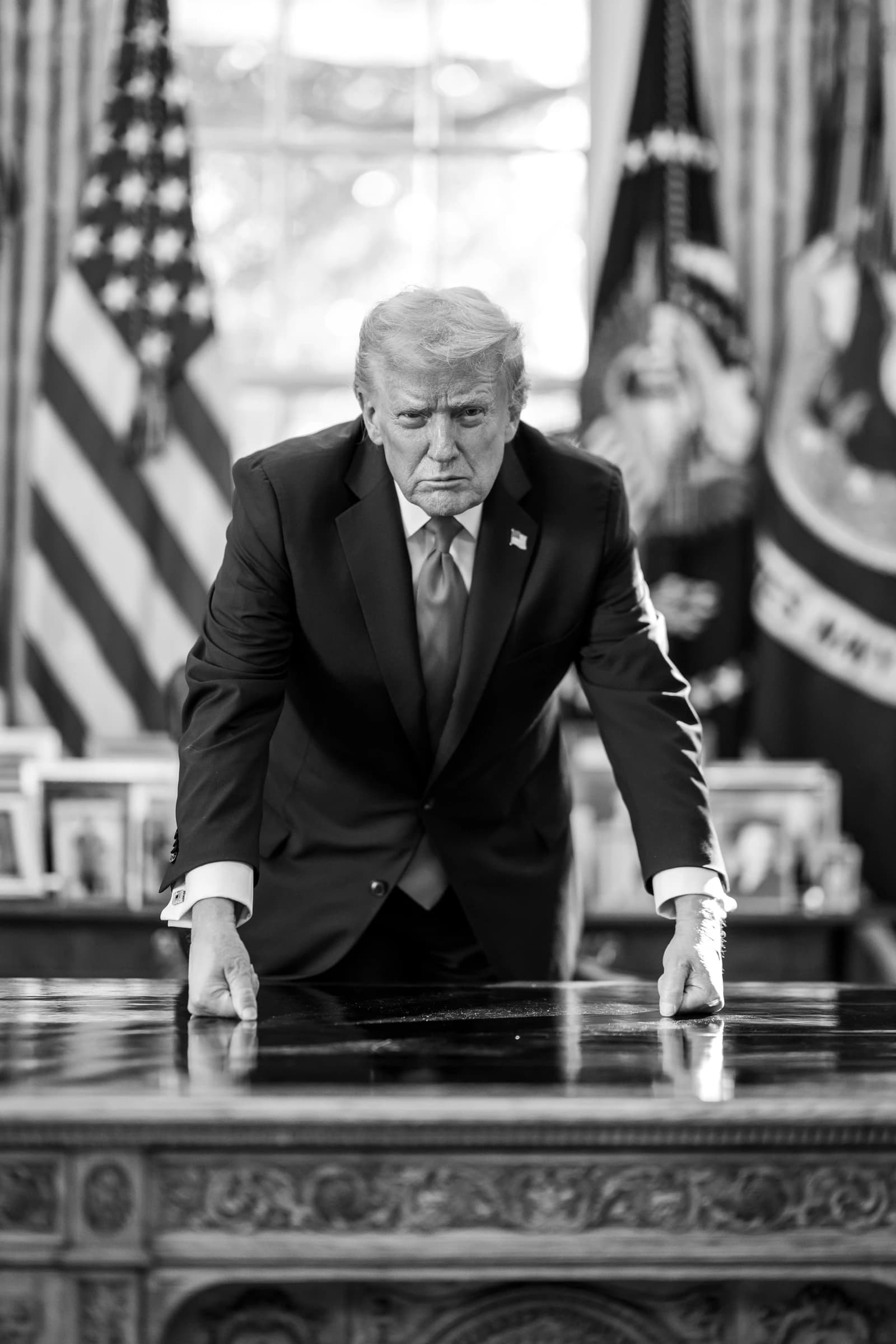 Donald Trump, former U.S. President, leans forward on a desk in an office.