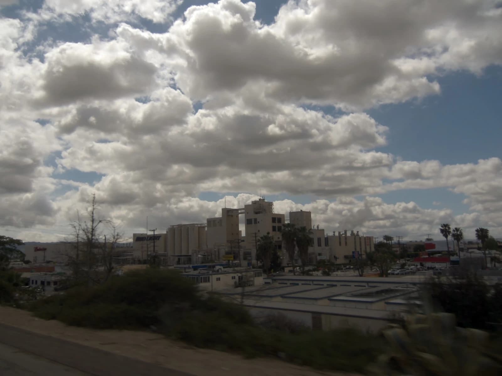 Exterior view of the Budweiser Brewery, a large industrial complex, under cloudy skies.