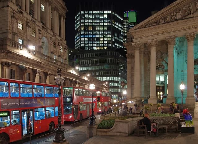 Bank of England building on Threadneedle Street, London, at night with red double-decker buses.