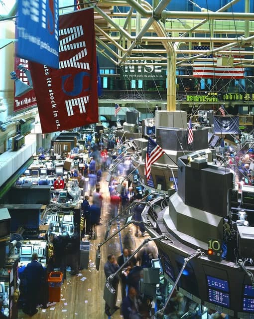 A busy trading floor of the New York Stock Exchange with brokers at workstations.
