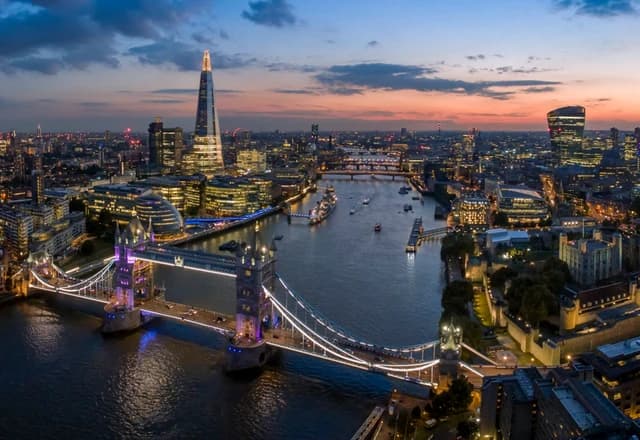 London skyline at dusk with Tower Bridge and the River Thames flowing through the city.