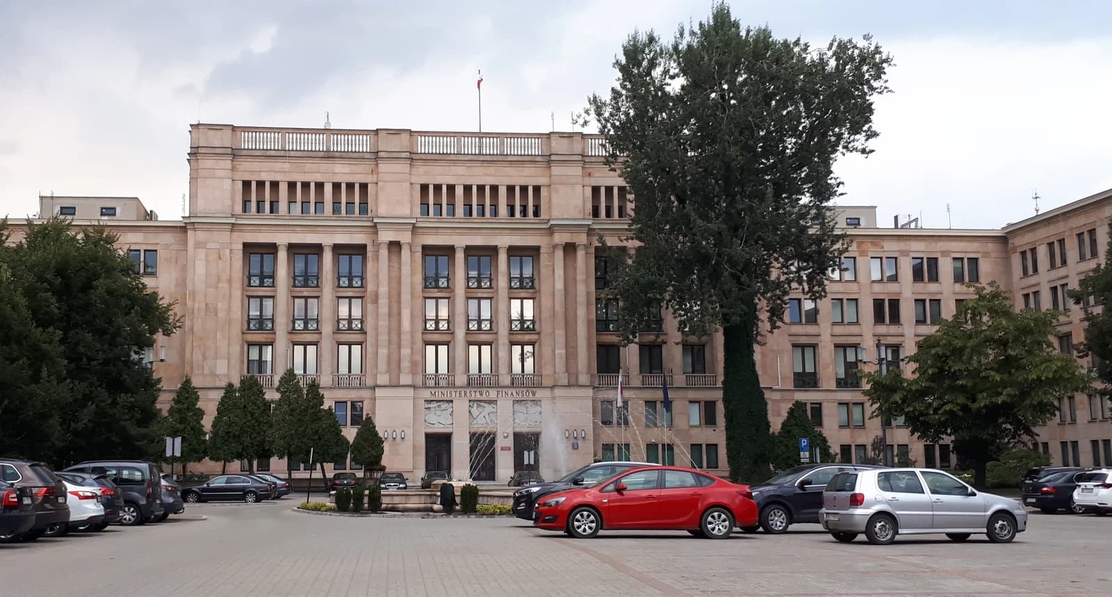 Polish Ministry of Finance building, a large stone structure, with parked cars in front.