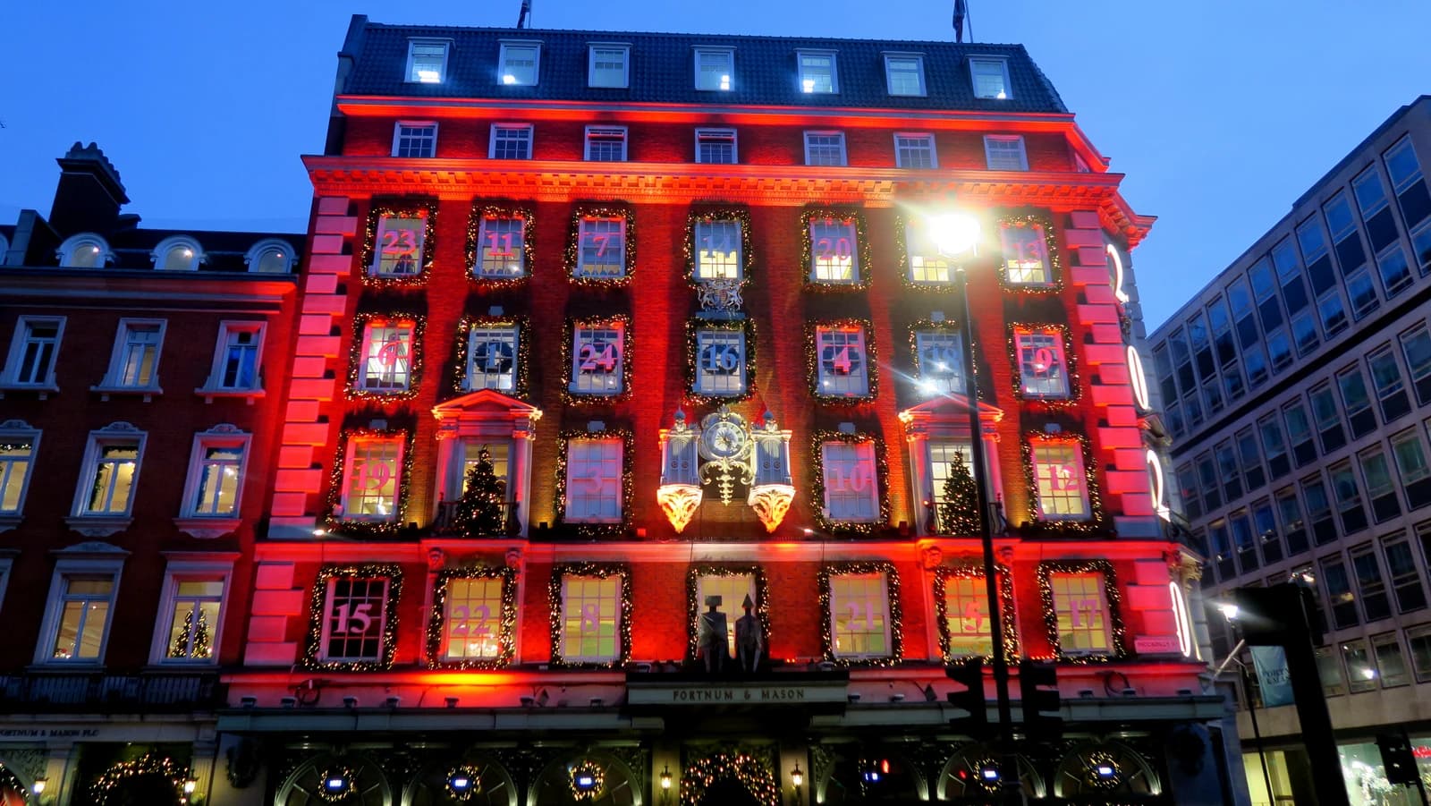 Fortnum & Mason department store in London lit up with red lights and Christmas decorations.