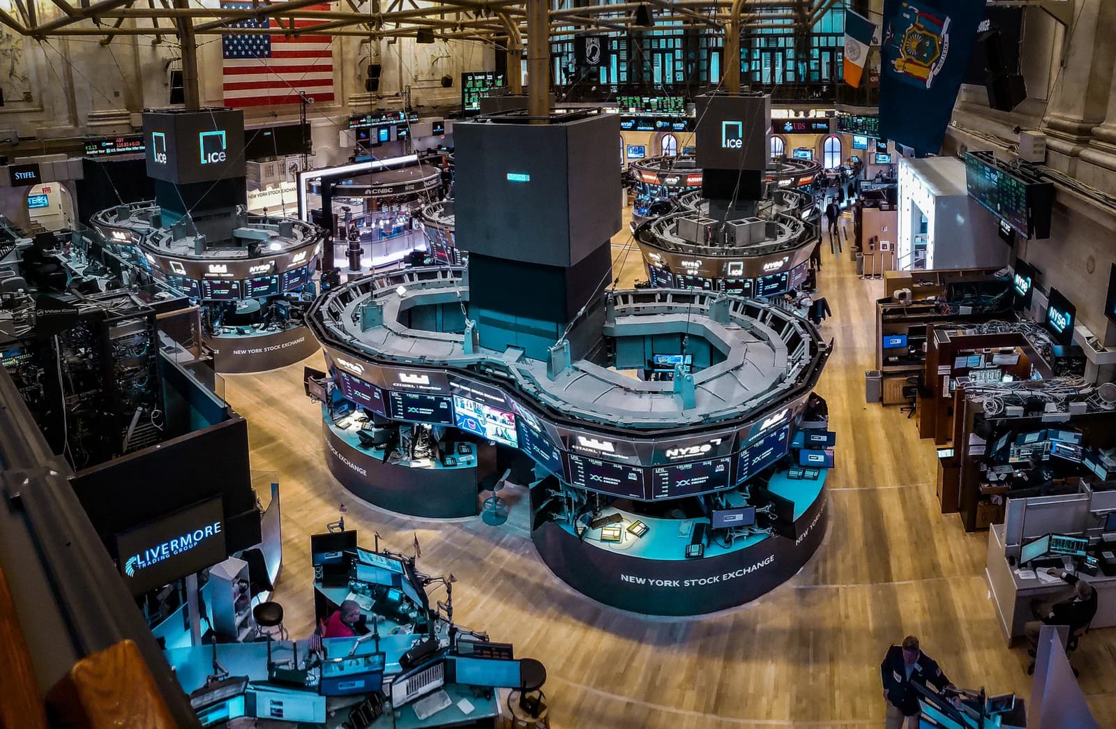 Overview of the New York Stock Exchange trading floor with desks and monitors.