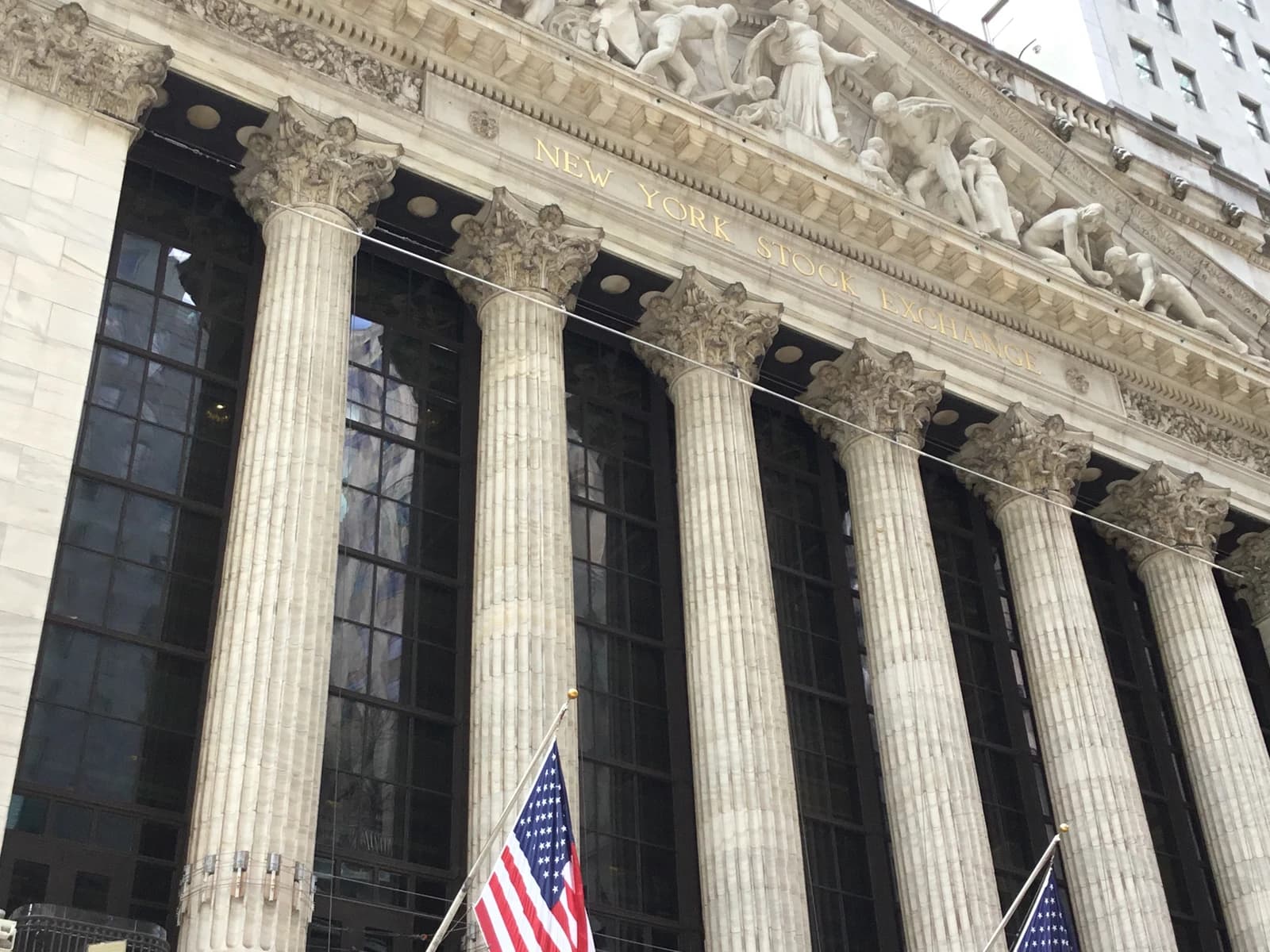 Exterior facade of the New York Stock Exchange building with pillars and statues.