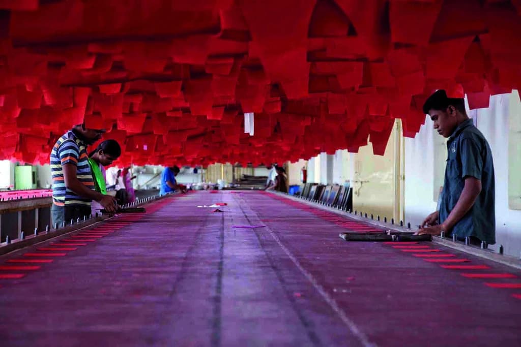 Textile factory workers in India performing manual printing operations.