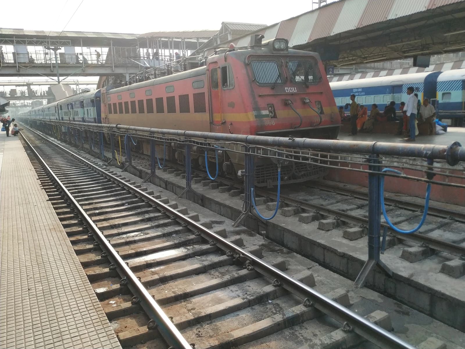 A red and yellow passenger train on the tracks at a railway station.