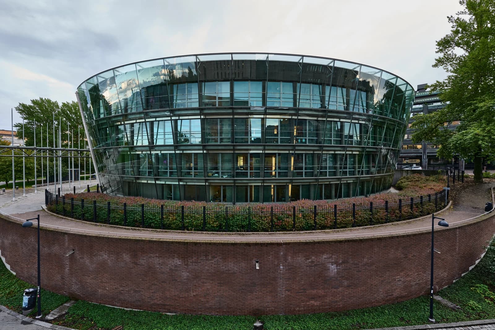 Exterior of the Pikkuparlamentti building in Helsinki, with glass facade and surrounding greenery.