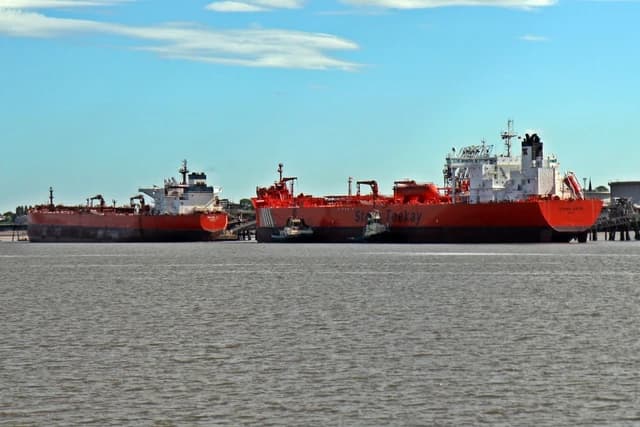 Three red and white oil tankers docked at an oil terminal.