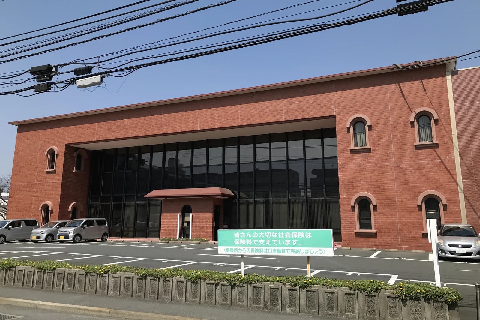Exterior view of the Japan Pension Service Kurume Office with cars parked outside.