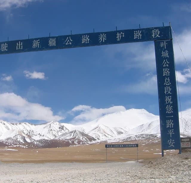 Road maintenance signs standing in a barren landscape with snow-capped mountains.