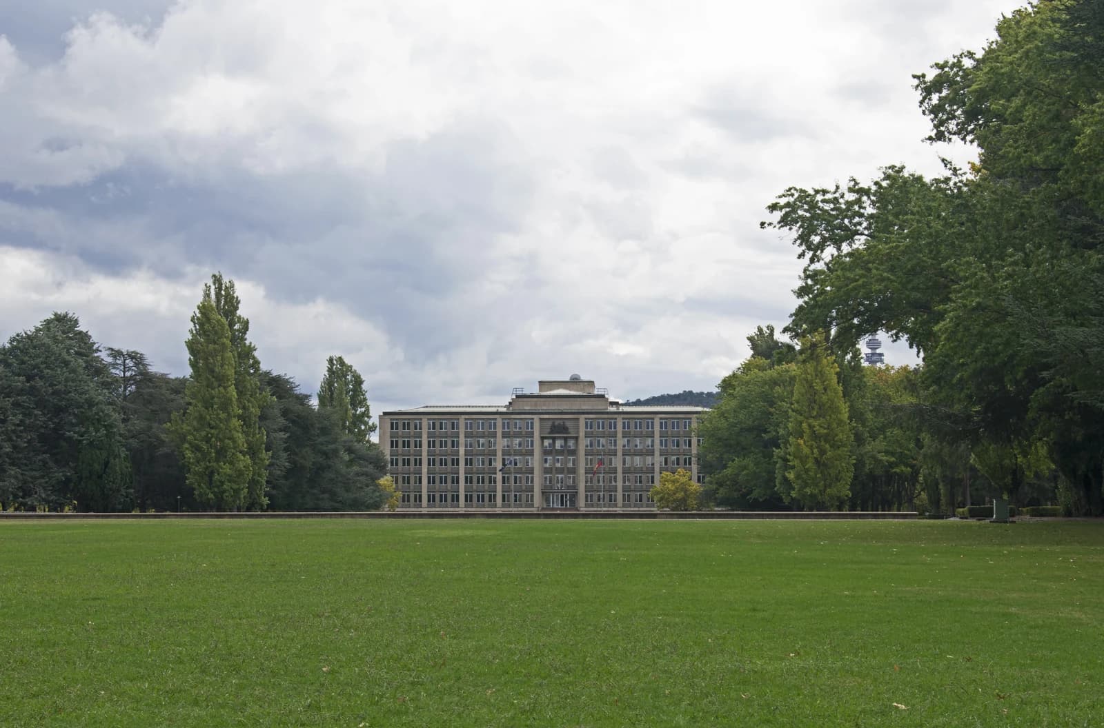 The Treasury Building in Canberra, Australia, seen across a green lawn on a cloudy day.