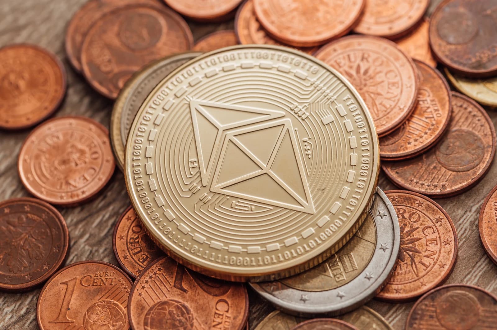 Close-up of a physical Ethereum cryptocurrency coin on a pile of Euro cents.