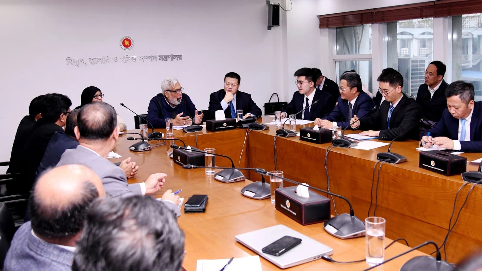 Chinese Delegation members and Bangladesh Ministry officials meeting at a conference table in Dhaka.