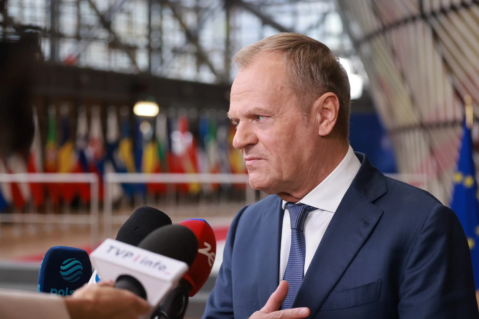 Donald Tusk, Polish Prime Minister, speaking into microphones at a summit.