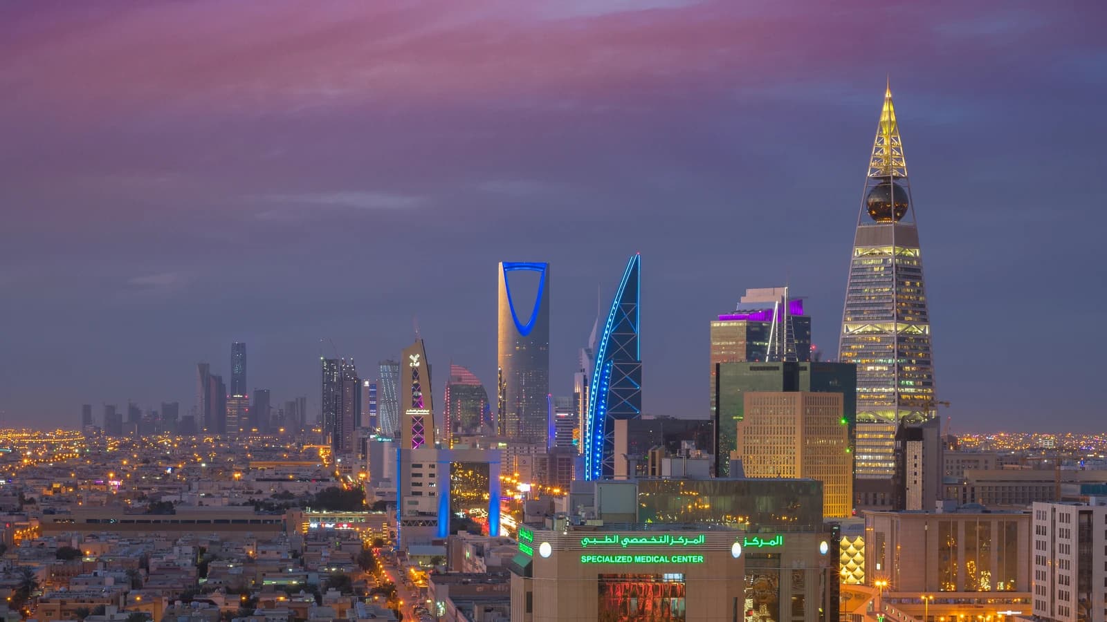 Riyadh city skyline at dusk with several illuminated modern skyscrapers.