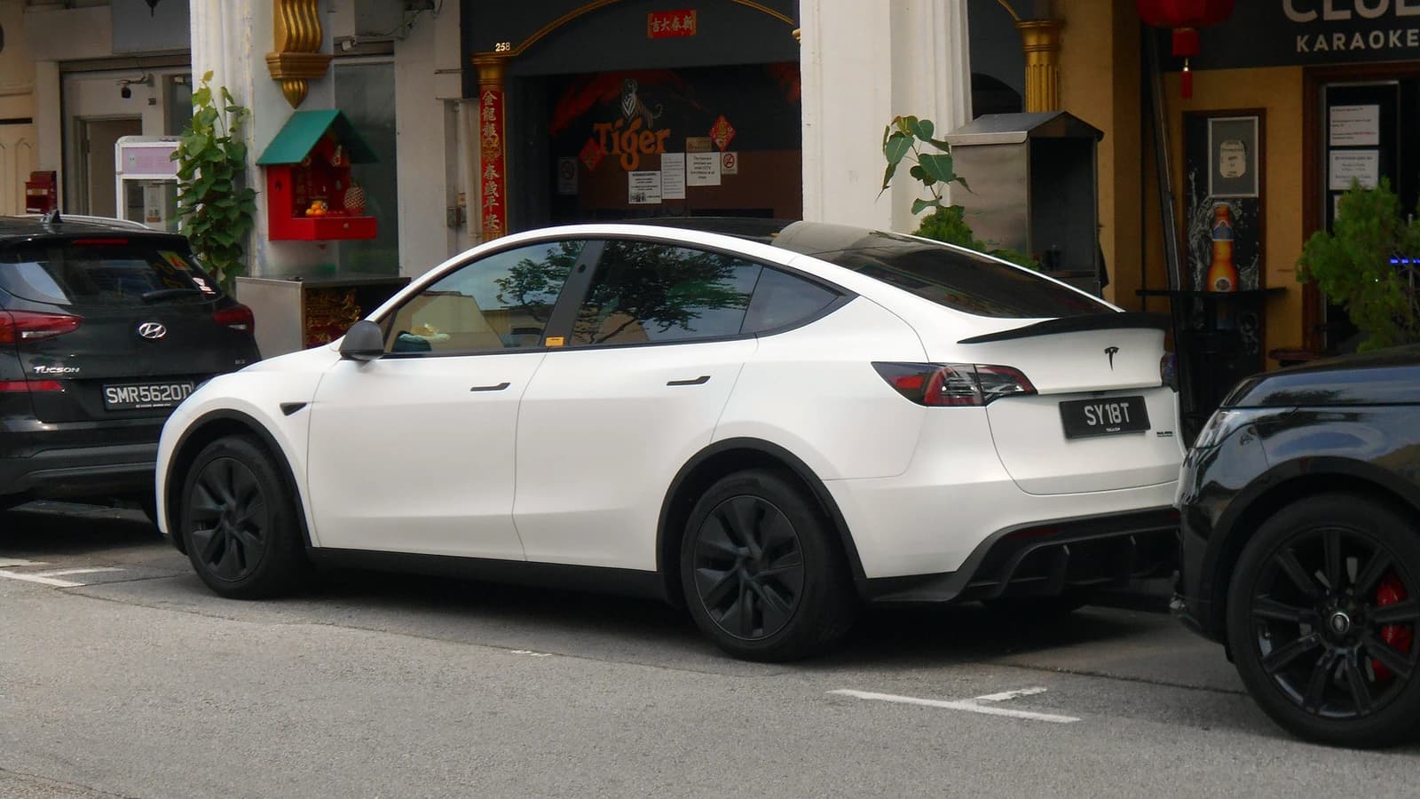 White Tesla Model Y electric vehicle parked on a street in Singapore.