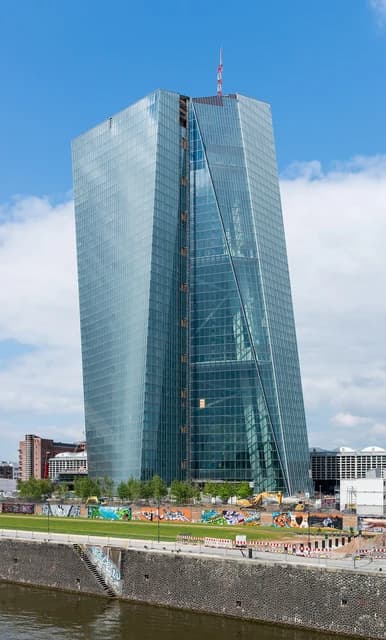 The European Central Bank building, a modern glass skyscraper, stands under blue sky.