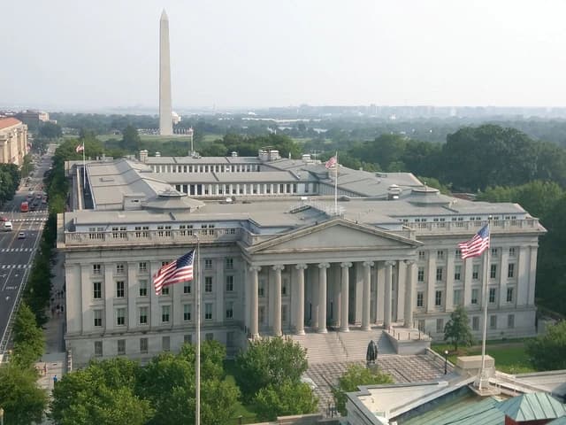 Aerial view of the United States Treasury Building, a large white stone structure with columns.