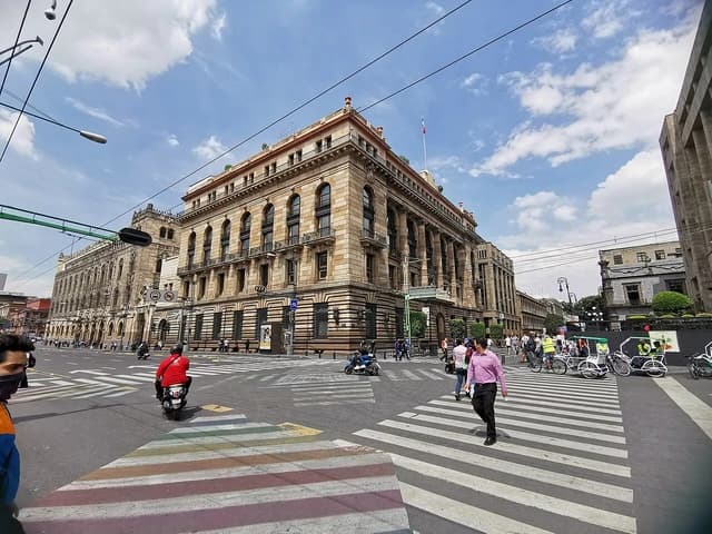 The Banco de Mexico building, a large ornate stone structure, on a street corner in Mexico City.