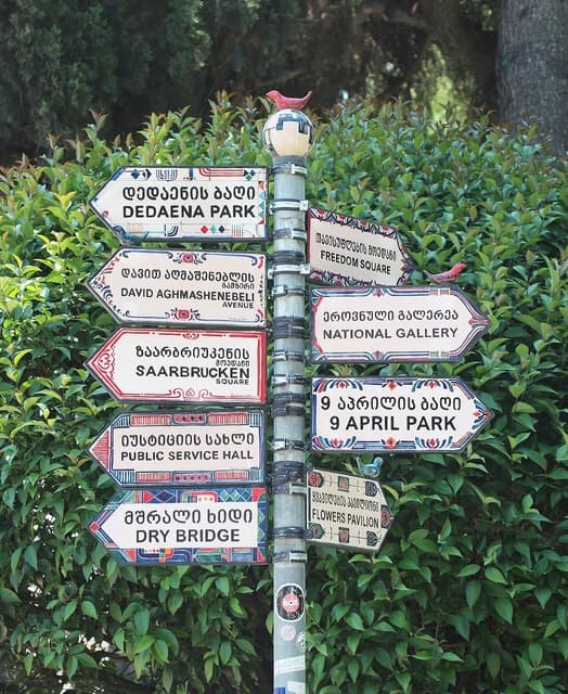 Decorative fingerposts with arrows pointing to different locations in Tbilisi, Georgia.