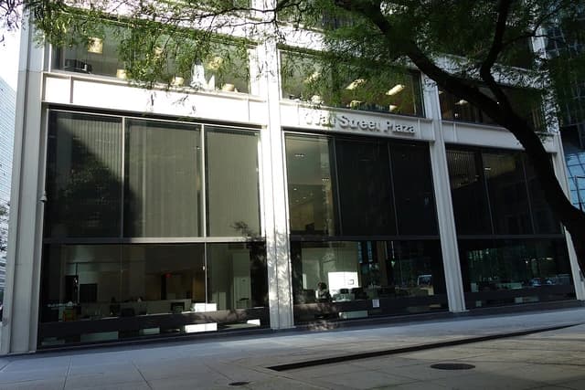 Exterior of Wall Street Plaza building with large windows and office interiors visible.