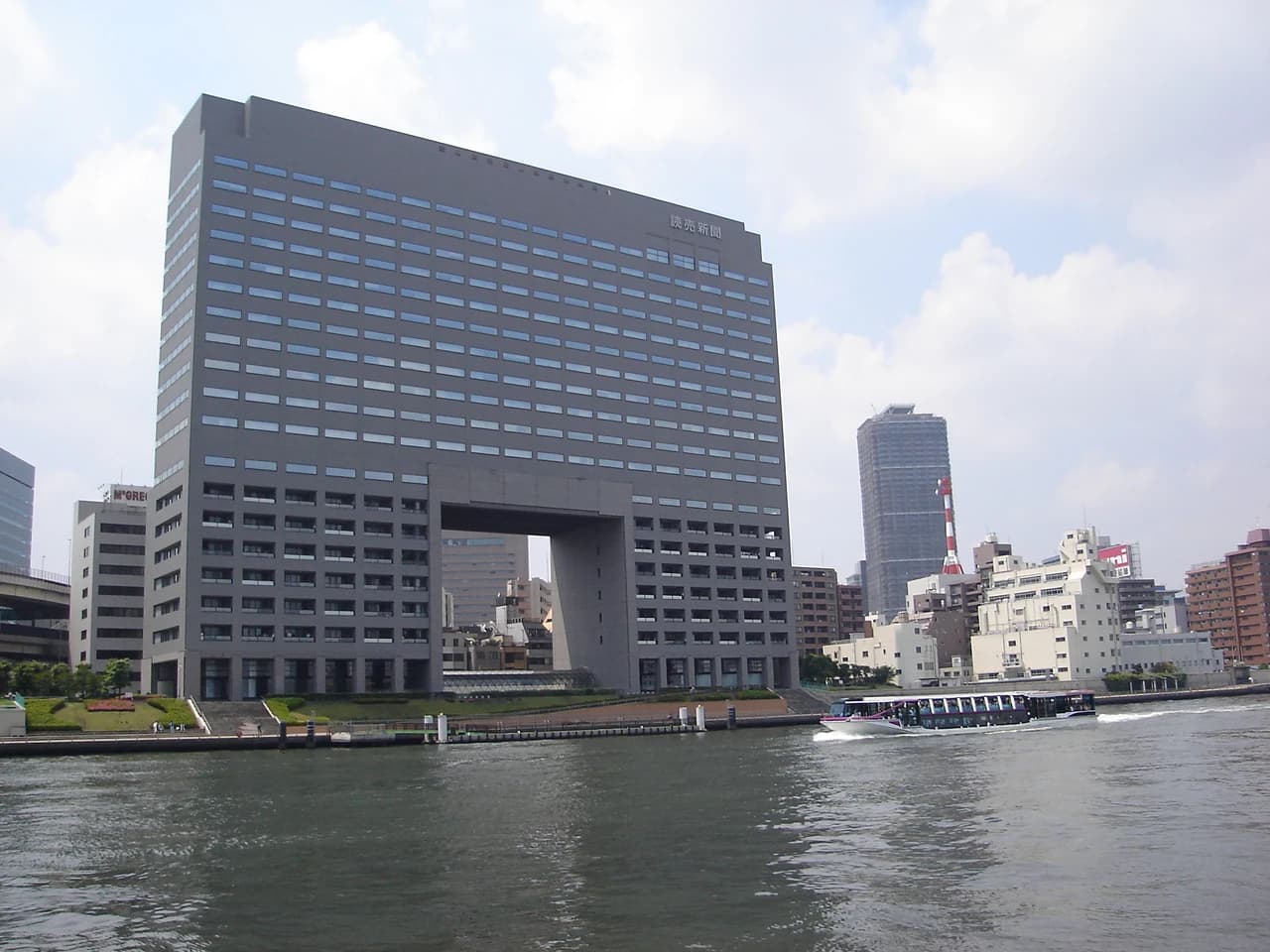 Yomiuri Shimbun Building with a boat on the river in the foreground.