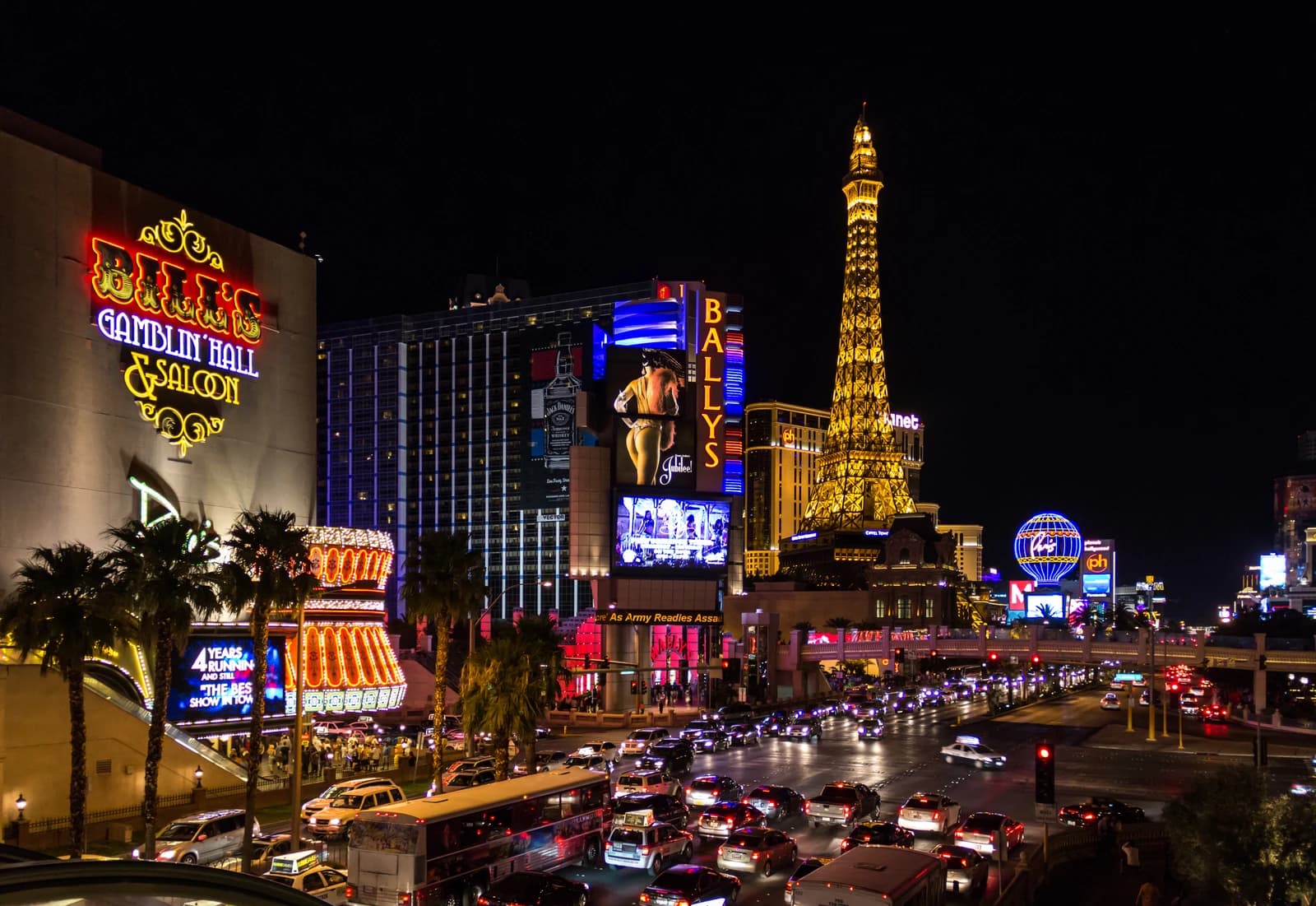 The Las Vegas Strip at night with neon signs and vehicle traffic.