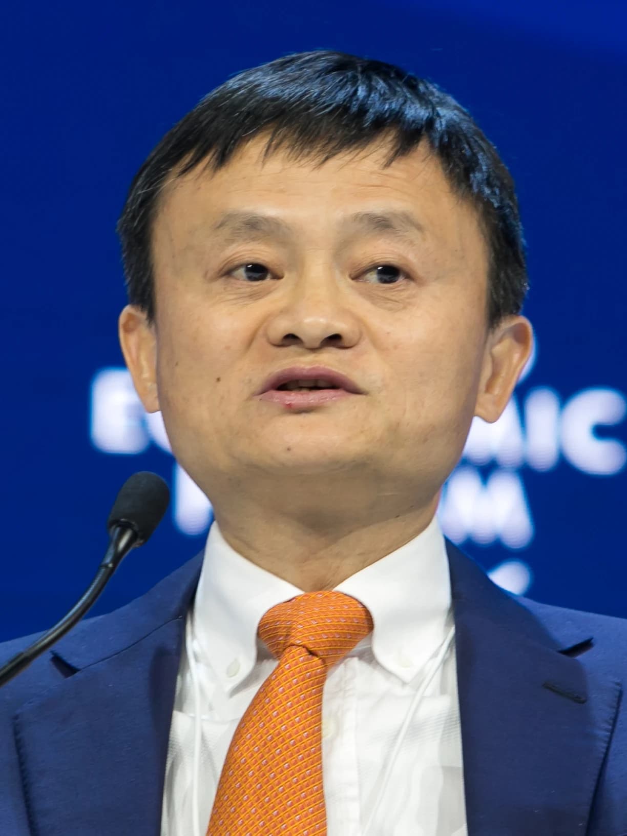 Jack Ma, founder of Alibaba, speaking into a microphone at a podium.