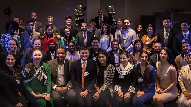 Jack Ma, founder of Alibaba, seated in the front row of a large group.