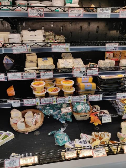 Trader Joe's cheese and hummus dips on display in a refrigerated grocery store aisle.