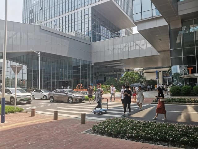 Exterior view of the Alibaba Shenzhen Branch building, with pedestrians and cars on the street.