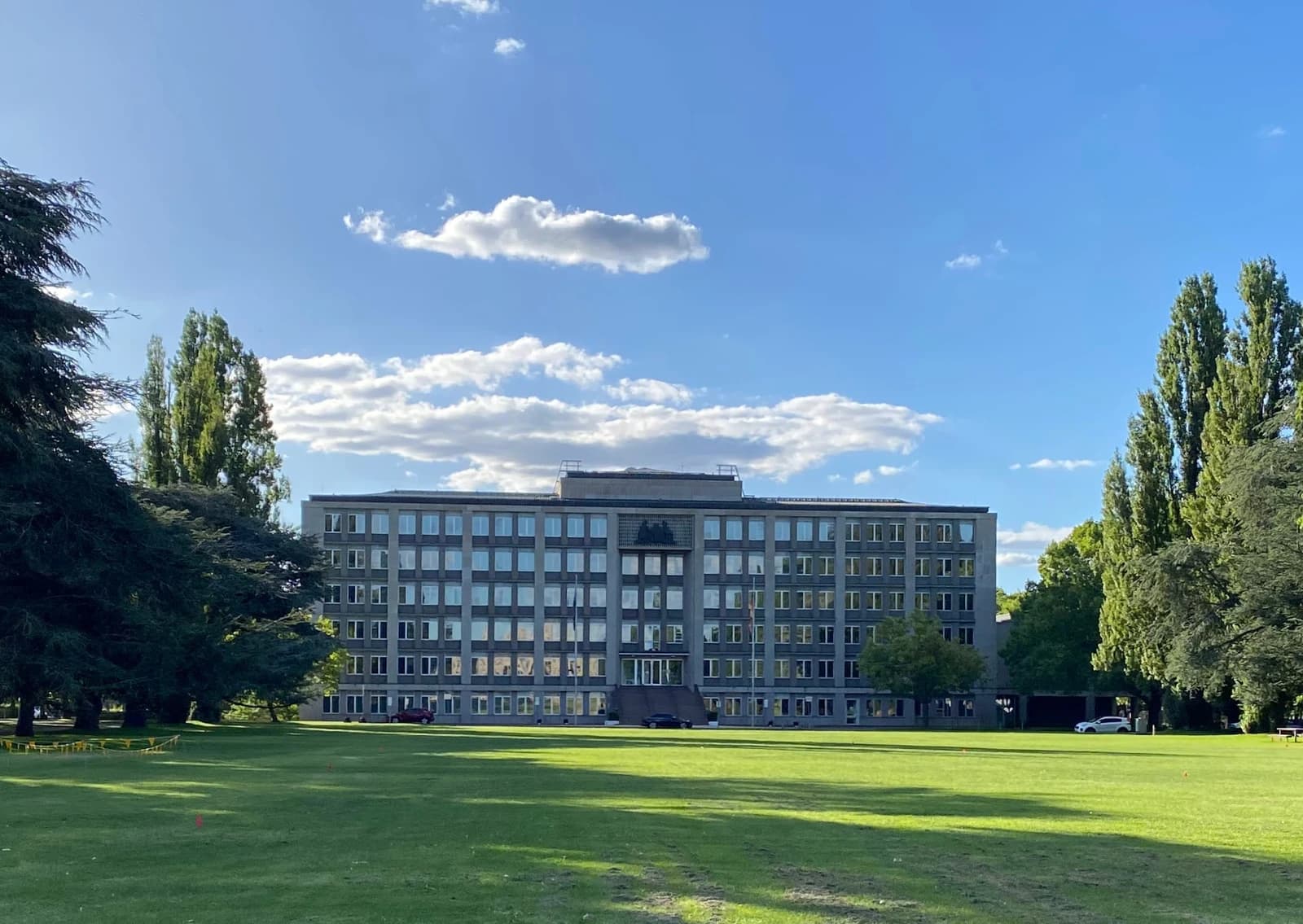 The Australian Treasury Building in Canberra under a blue sky with scattered clouds.