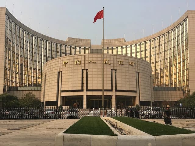 The People's Bank of China headquarters building in Beijing with a Chinese flag.