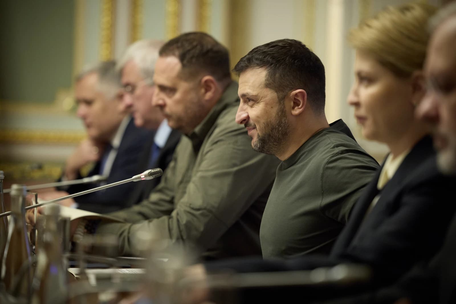 Ukrainian President Volodymyr Zelenskyy, in an olive shirt, seated at a meeting.