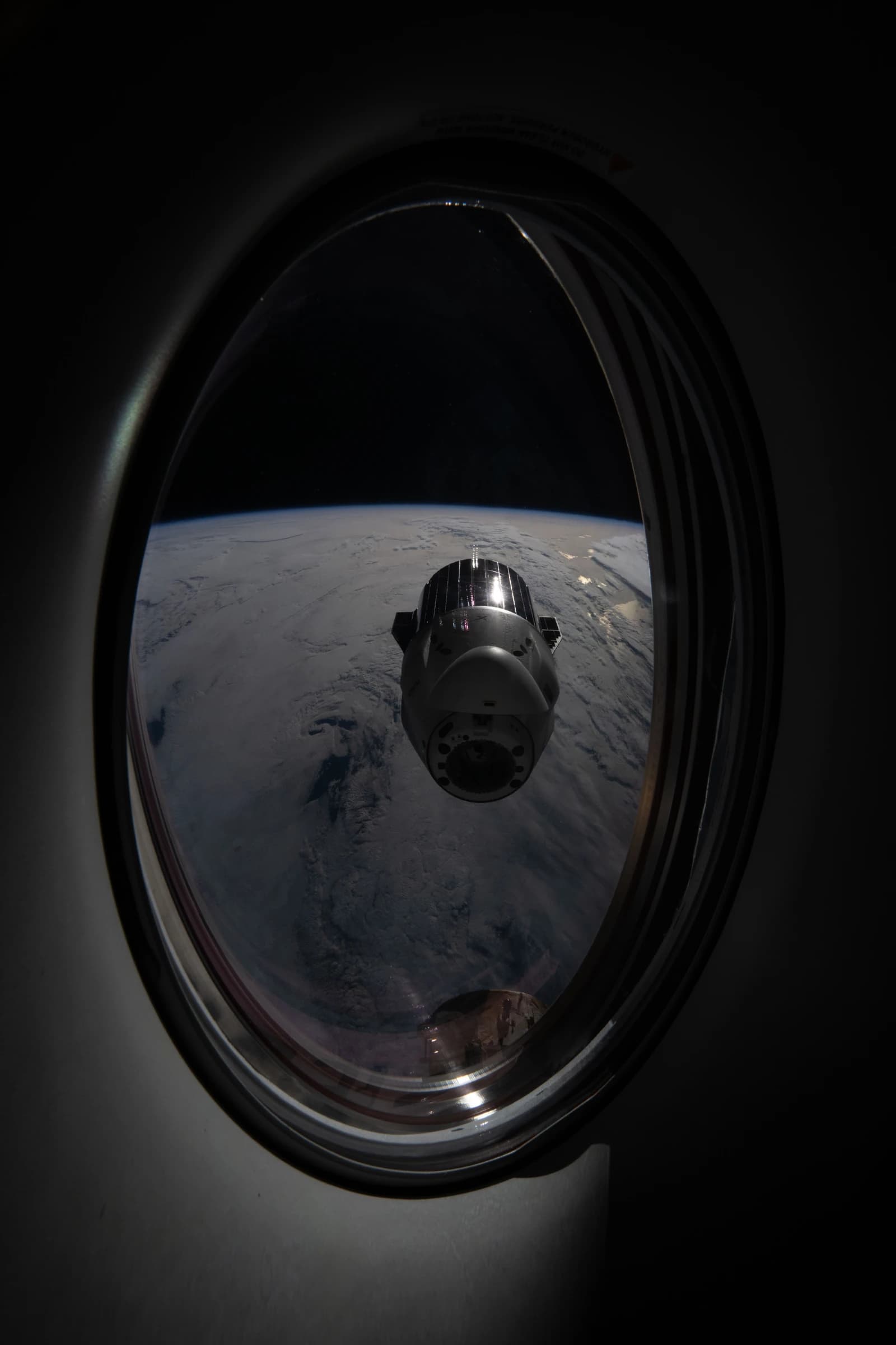 A SpaceX Dragon cargo spacecraft is seen departing Earth from a spacecraft window.