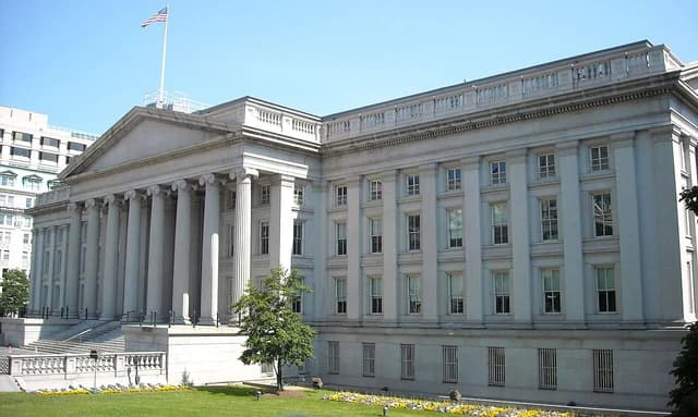 Exterior view of the U.S. Treasury Department building with a US flag flying.