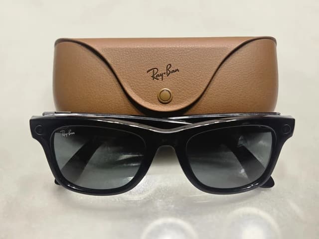 Black Ray-Ban Meta Gen 1 smart glasses next to a brown charging case.