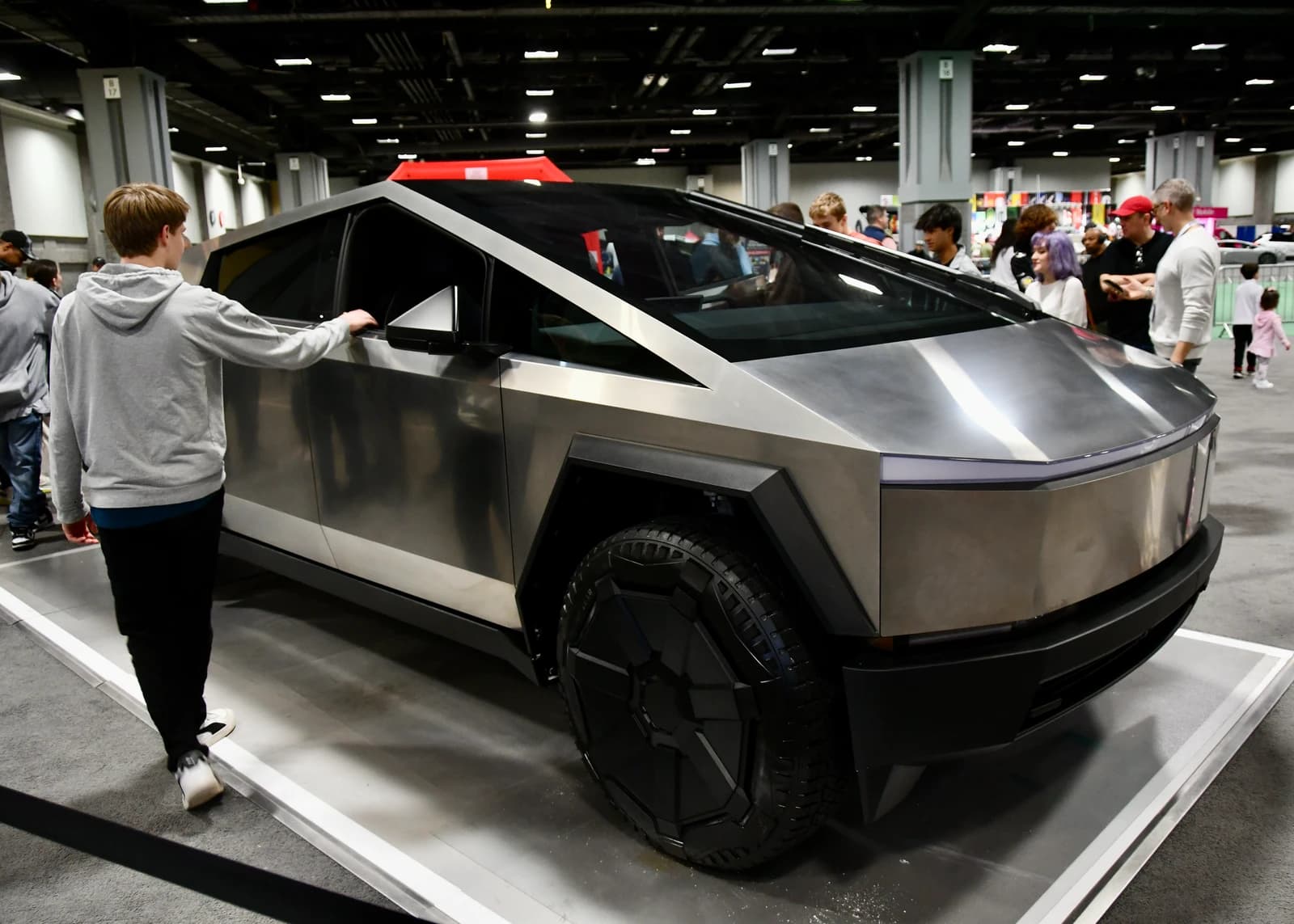 A person viewing a Tesla Cybertruck from the side at an indoor event.