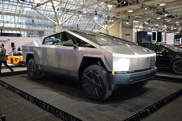 Tesla Cybertruck, a silver electric pickup truck, on display at an auto show.